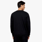 The back view of a model wearing a black crewneck sweatshirt. The sweatshirt is plain with no visible logos or embellishments on the back. The model is paired with matching black joggers, keeping the outfit cohesive and minimal