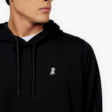 Close-up view of a man wearing a black hoodie with a small embroidered logo on the chest, featuring a white graphic of a dog. The hoodie includes black drawstrings and is layered over a white t-shirt." Let me know if you'd like adjustments