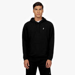 Front view of a man wearing a black hoodie featuring a kangaroo pocket, drawstring, and a small embroidered white dog logo on the chest. The outfit is paired with matching black sweatpants, and the man is standing against a plain white background." Let me know if you'd like any adjustments