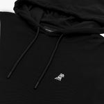 A close-up of a black hoodie highlighting its details. The hoodie features a drawstring hood with black cords and matching aglets. A small embroidered logo of a dog wearing a hat is stitched on the left chest area in white. The fabric has a textured weave, and the neckline reveals a "James Bark" brand label. The hood is slightly folded, showcasing its interior lining.