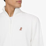 Close-up of a man wearing a white half-zip sweatshirt, highlighting the small embroidered dog logo on the left chest. The fabric has a textured pattern, and the zipper is partially open, revealing a white undershirt. The background is plain white