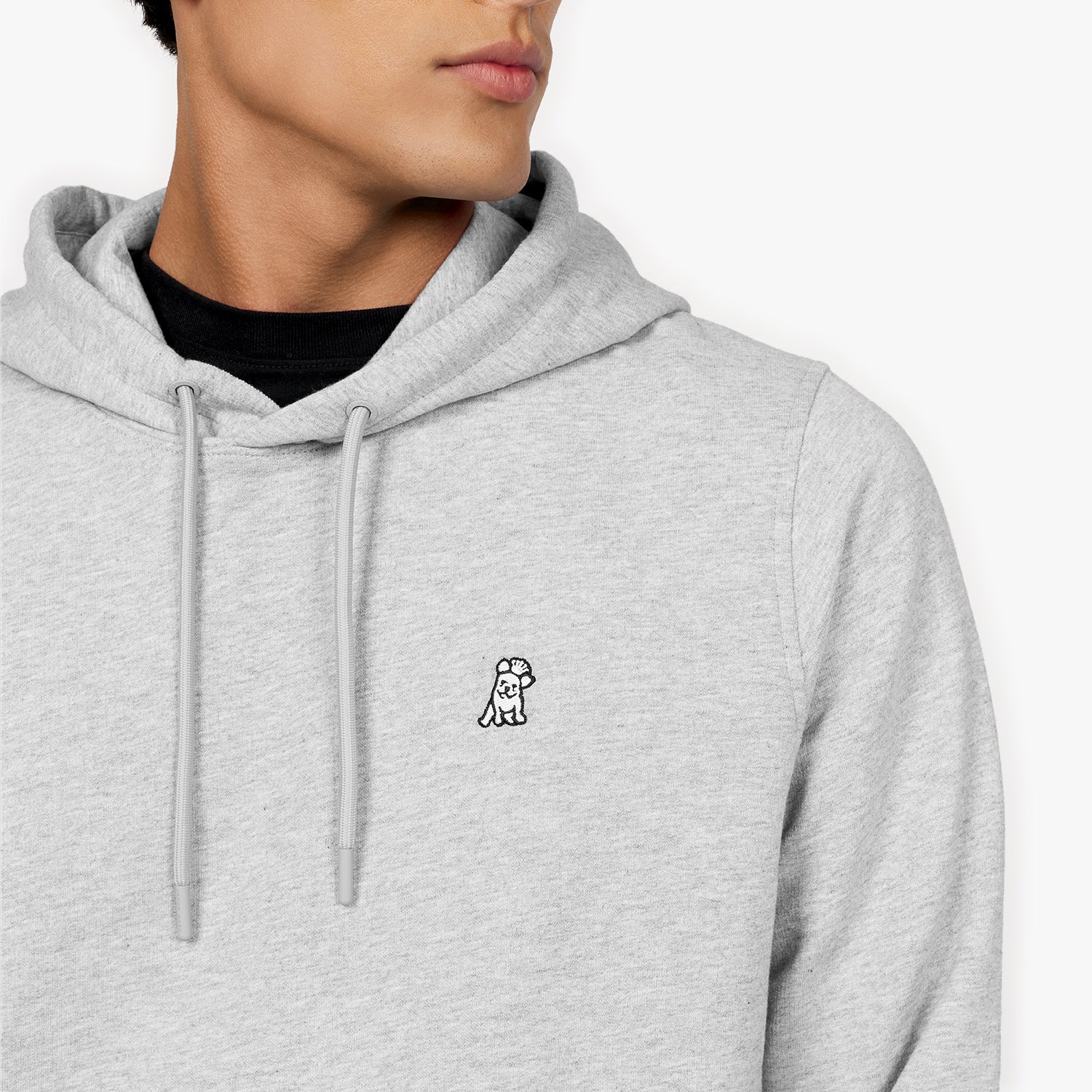 Close-up of a man wearing a light gray hoodie featuring an embroidered black and white dog logo on the chest. The hoodie includes drawstrings and is paired with a black undershirt, displayed against a plain white background." Let me know if you'd like any changes