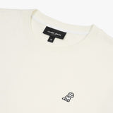 Close-up of the neckline and embroidered dog logo on the cream-colored sweatshirt, highlighting the fine details and texture