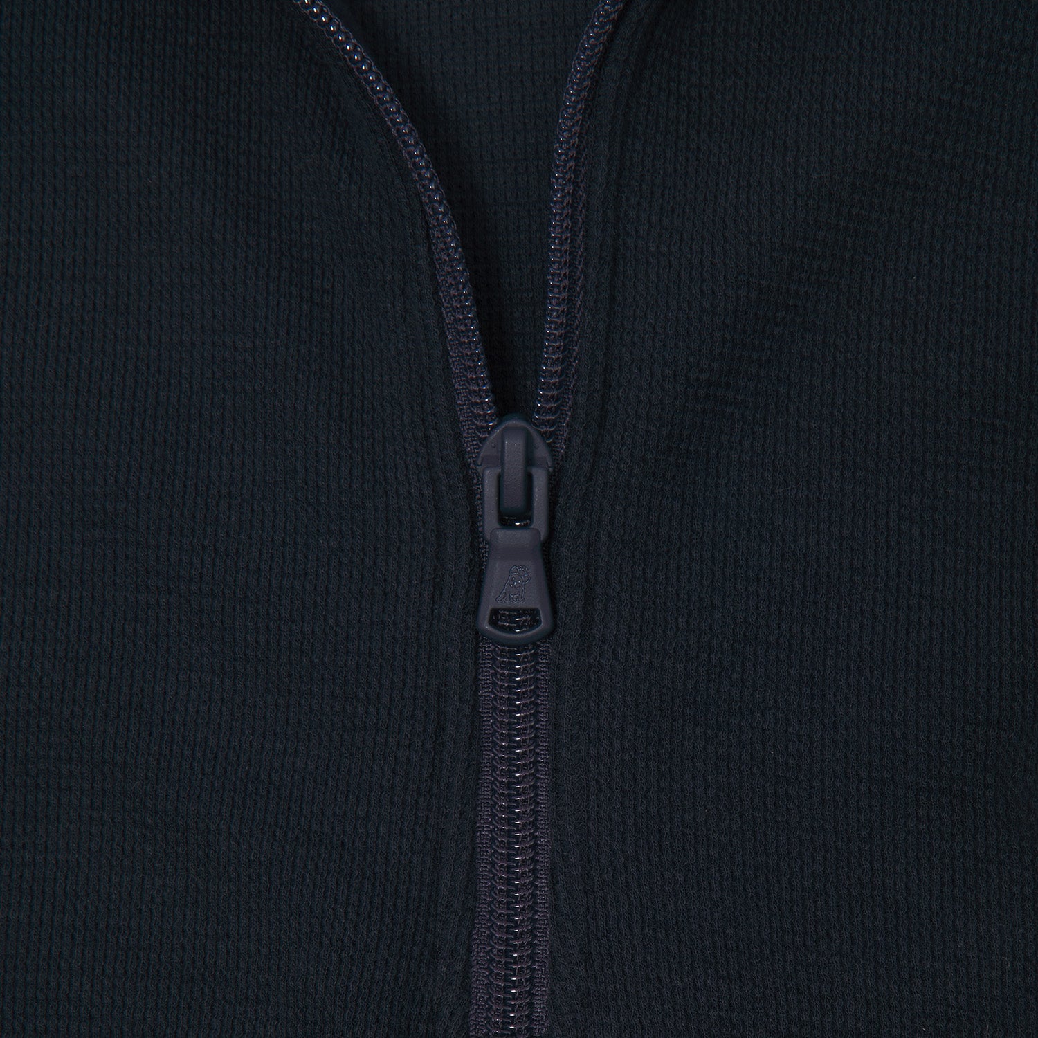 Extreme close-up of a navy blue quarter-zip pullover's zipper. The zipper pull is embossed with a small dog logo, blending seamlessly with the textured fabric