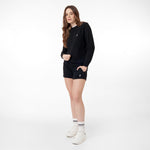 Side view of a woman wearing the black crewneck sweatshirt paired with black shorts, white socks and White shoes