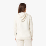 Back view of a woman wearing a cream-colored hoodie with matching sweatpants, showcasing the simple design and relaxed fit of the hoodie.