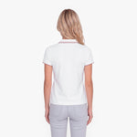 Back view of a woman wearing a white polo with an embroidered dog logo on a white background