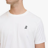 A close-up of a man wearing a white T-shirt with a small black embroidered dog logo on the left chest