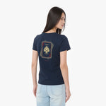A woman shown from the back wearing a navy blue T-shirt with a gold and red playing card graphic on the back