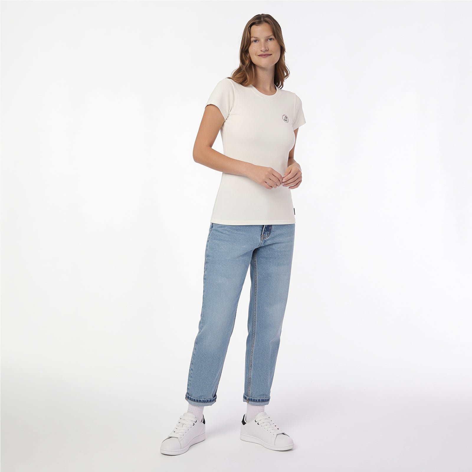 A woman modeling a T-shirt in off-white, paired with light-wash blue jeans and white sneakers