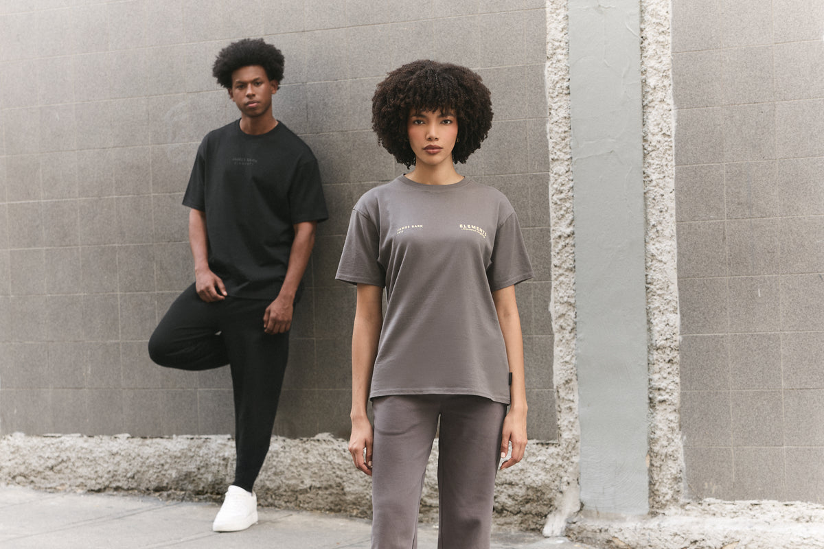 Two models standing against a gray concrete wall