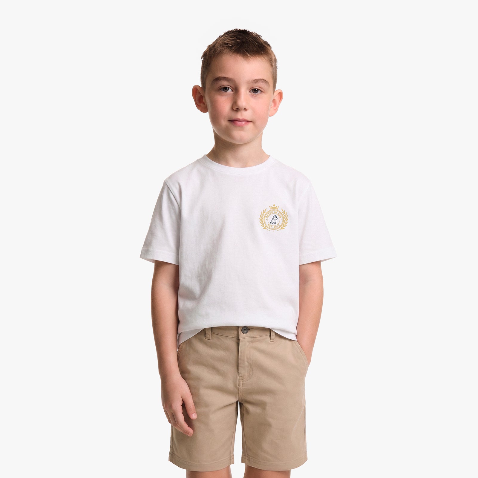 A young boy wearing a white T-shirt with a small gold and blue crest on the left chest