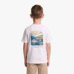 A child viewed from behind, wearing a white T-shirt with a large multicolor graphic print on the back featuring a yacht and coastal scene