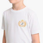 A child wearing a white short-sleeve T-shirt with a gold and navy blue emblem printed on the left chest.