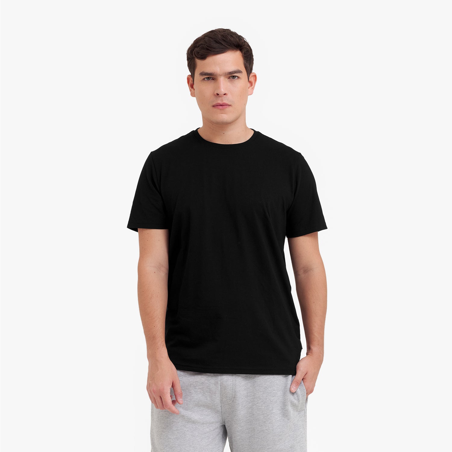 Man wearing a black t-shirt and gray pants on a white background