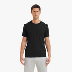Man wearing a black t-shirt and gray pants on a white background