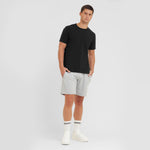Man wearing a black t-shirt and gray shorts on a white background