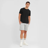 Man wearing a black t-shirt and gray shorts on a white background