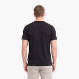 A man viewed from behind wearing a black short-sleeve crewneck t-shirt.