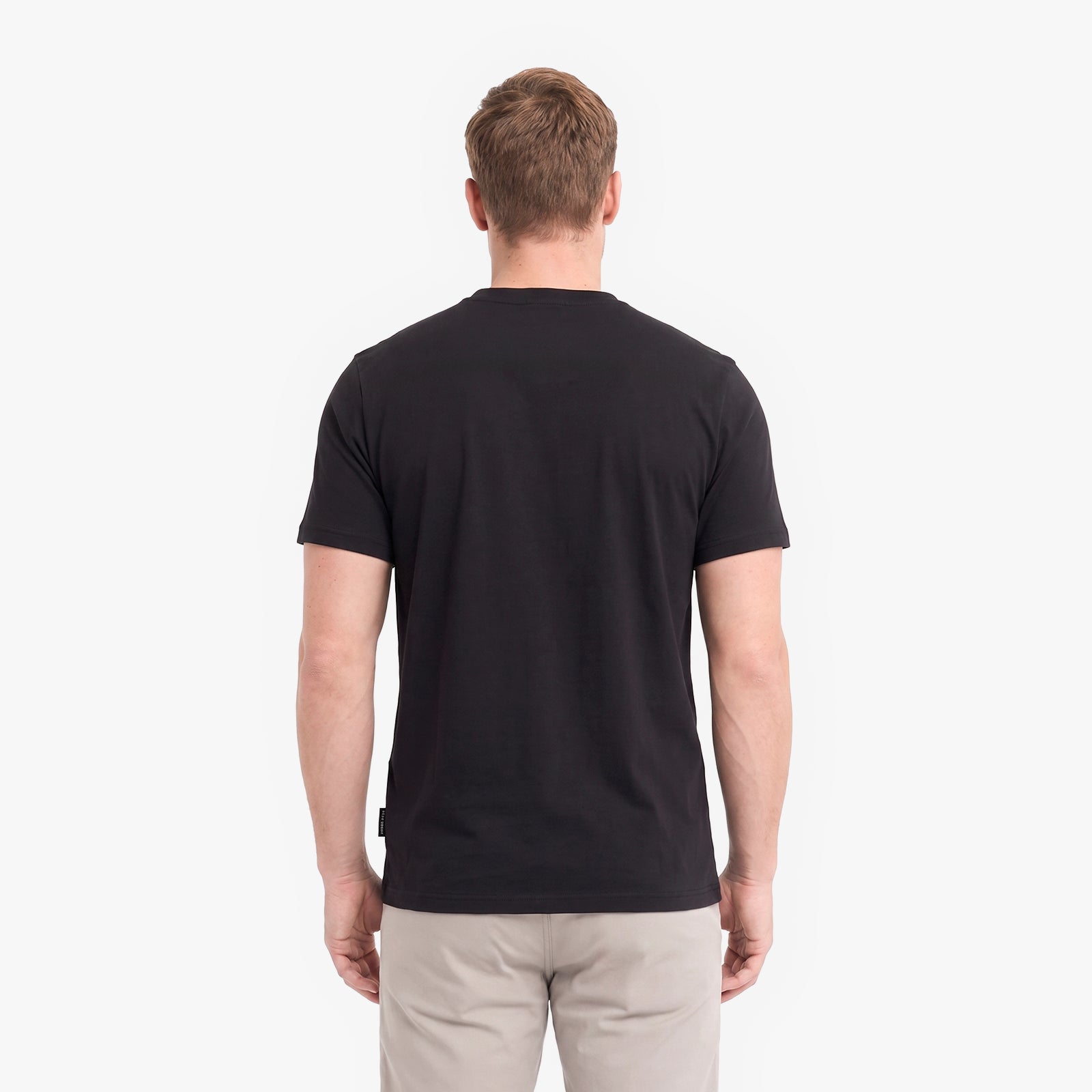 A man viewed from behind wearing a black short-sleeve crewneck t-shirt.