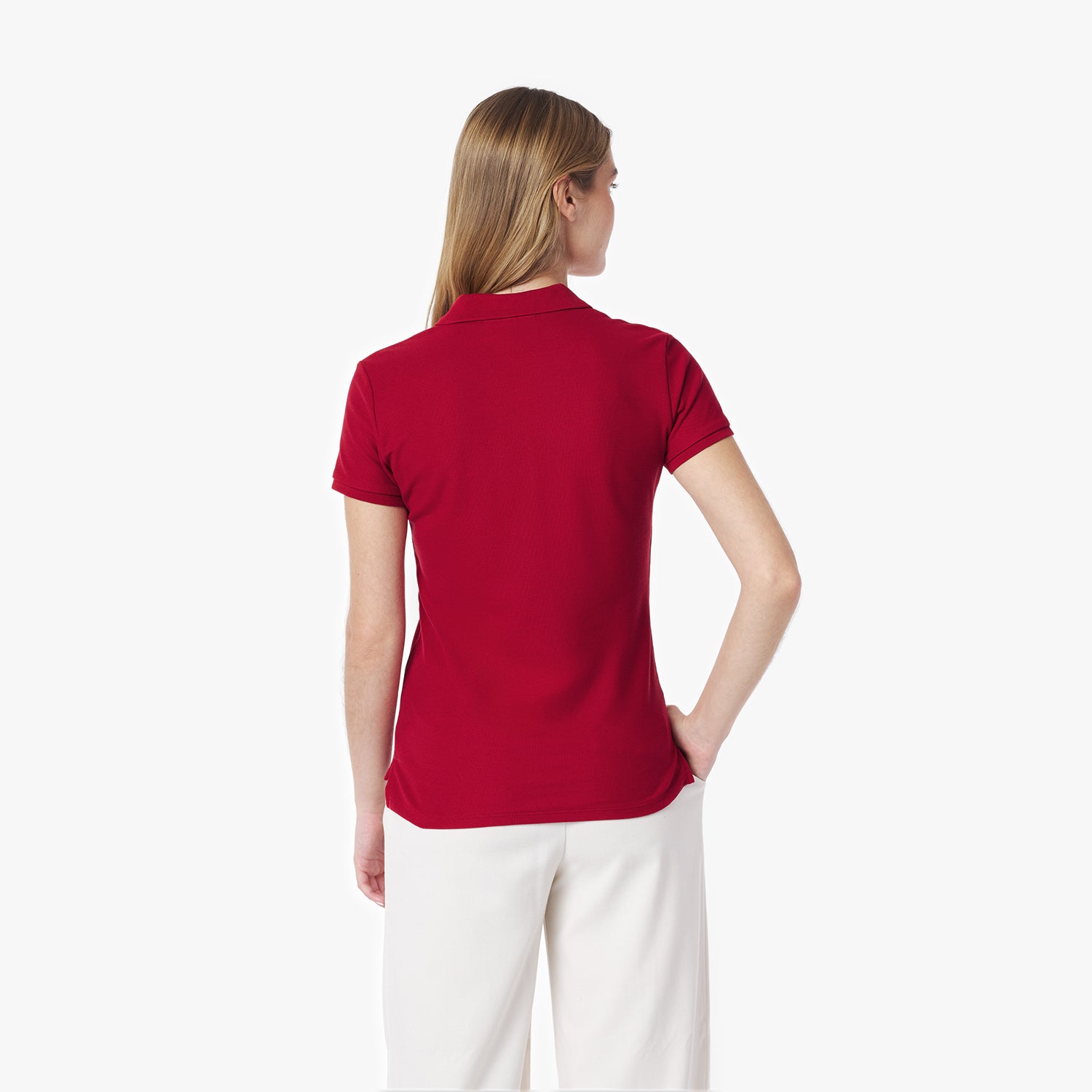Back of woman wearing a red polo shirt and white pants on a white background