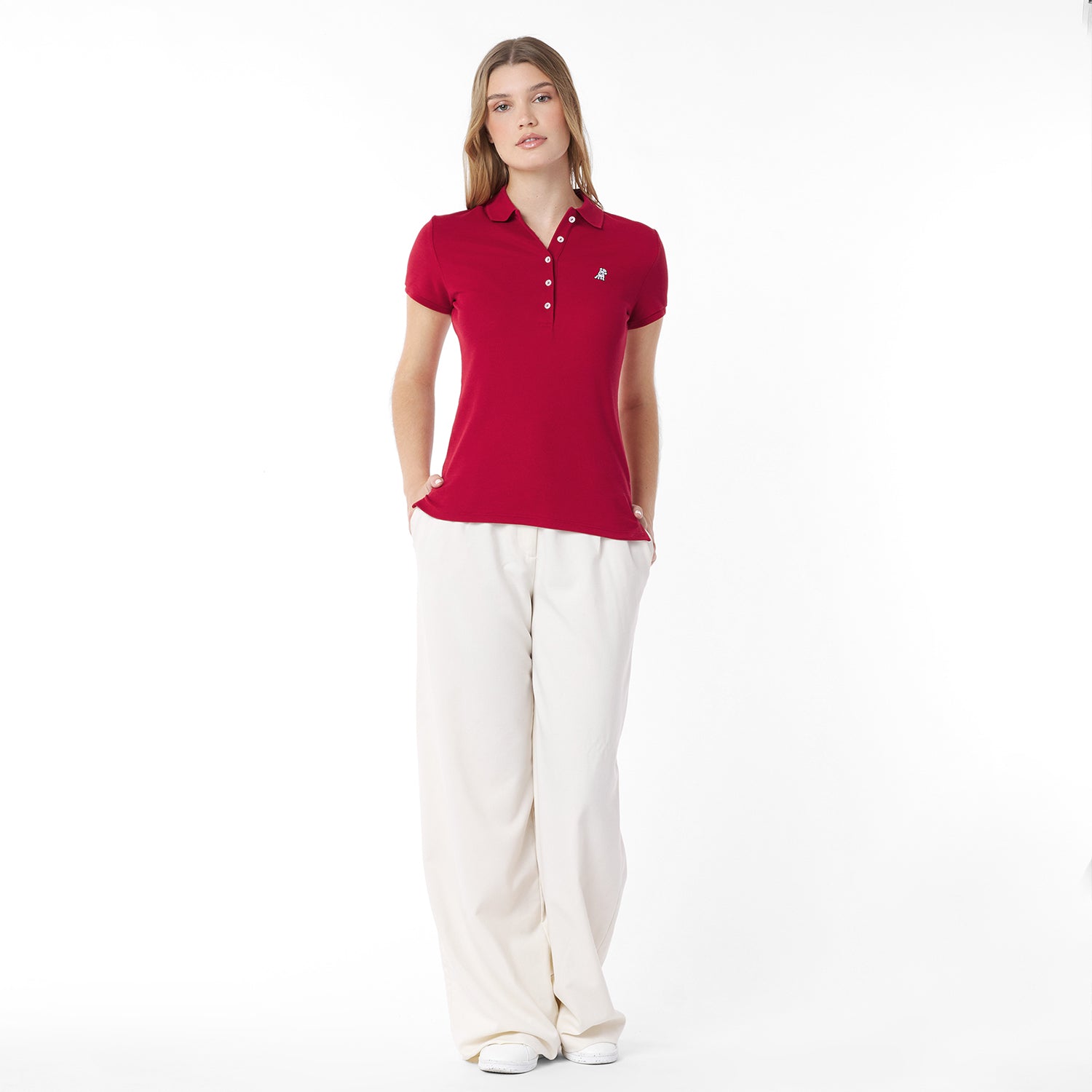 Full body picture of a woman wearing a red polo shirt and white pants on a white background
