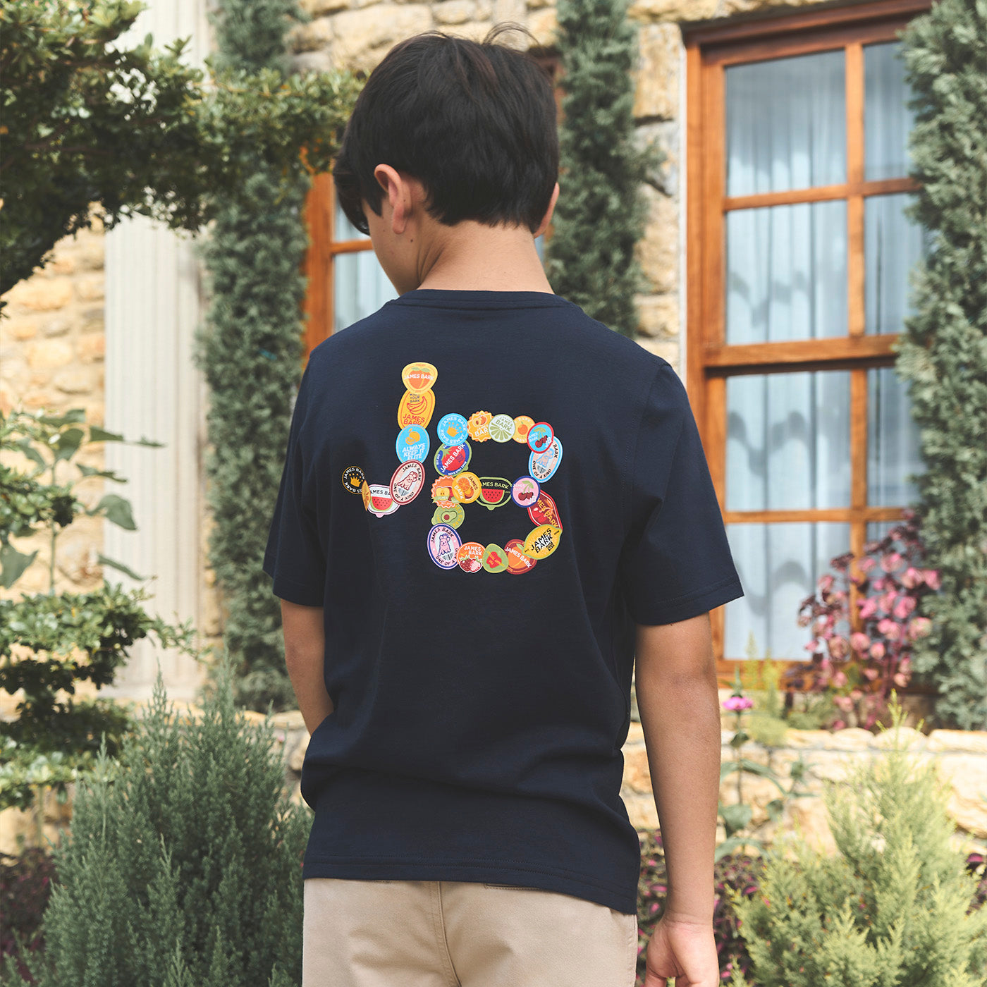 Person wearing a navy blue t-shirt with colorful design on the back, standing outdoors.