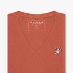 Front view of a terracotta-colored women's V-neck t-shirt laid flat against a white background, showing the short sleeves and the black and white embroidered logo on the left chest