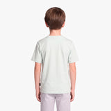 A child viewed from the back wearing a light green T-shirt and light gray pants