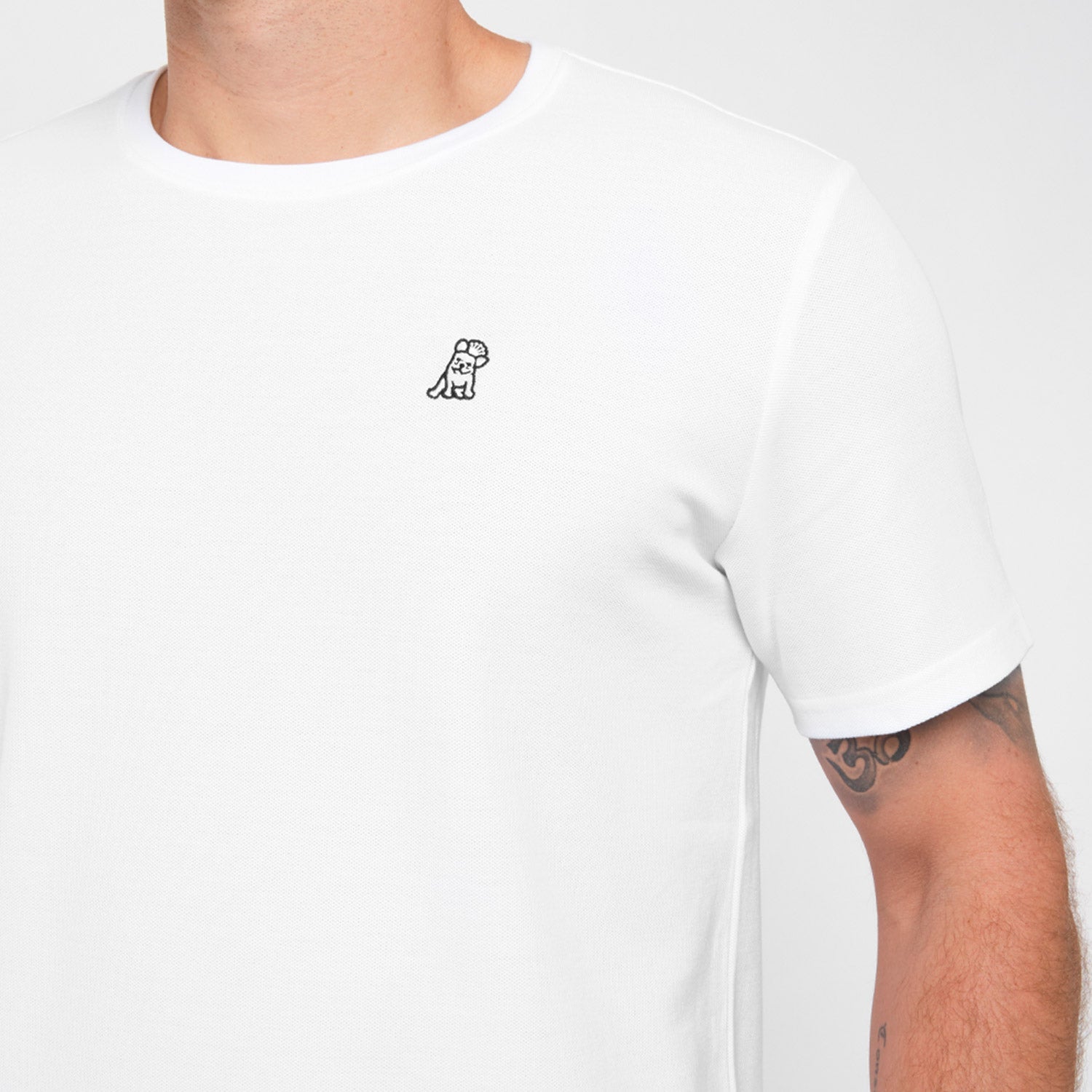 Close-up of a man wearing the white T-shirt, showing the small embroidered logo on the chest.