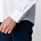 Close-up of the sleeve of the white button-up shirt: The image focuses on the cuff and the man's hand as he adjusts his sleeve.