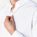 Close-up of a man adjusting the collar of the white shirt: The image focuses on the upper body and collar, with the man adjusting the buttons near his chest.