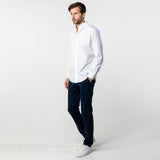 Full-body view of a man wearing the white button-up shirt and dark pants: The man is standing with one hand in his pocket, showing the full outfit from head to toe.